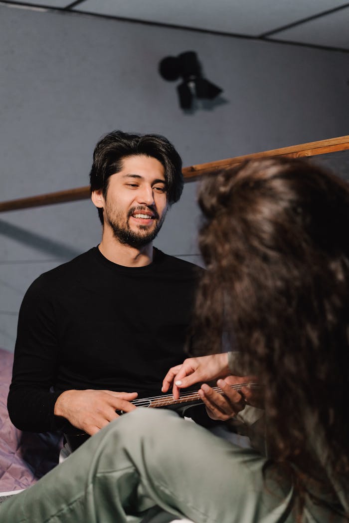 A young couple enjoying quality time and music indoors with a ukulele.